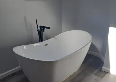White freestanding soaking tub with black matte faucet in modern bathroom