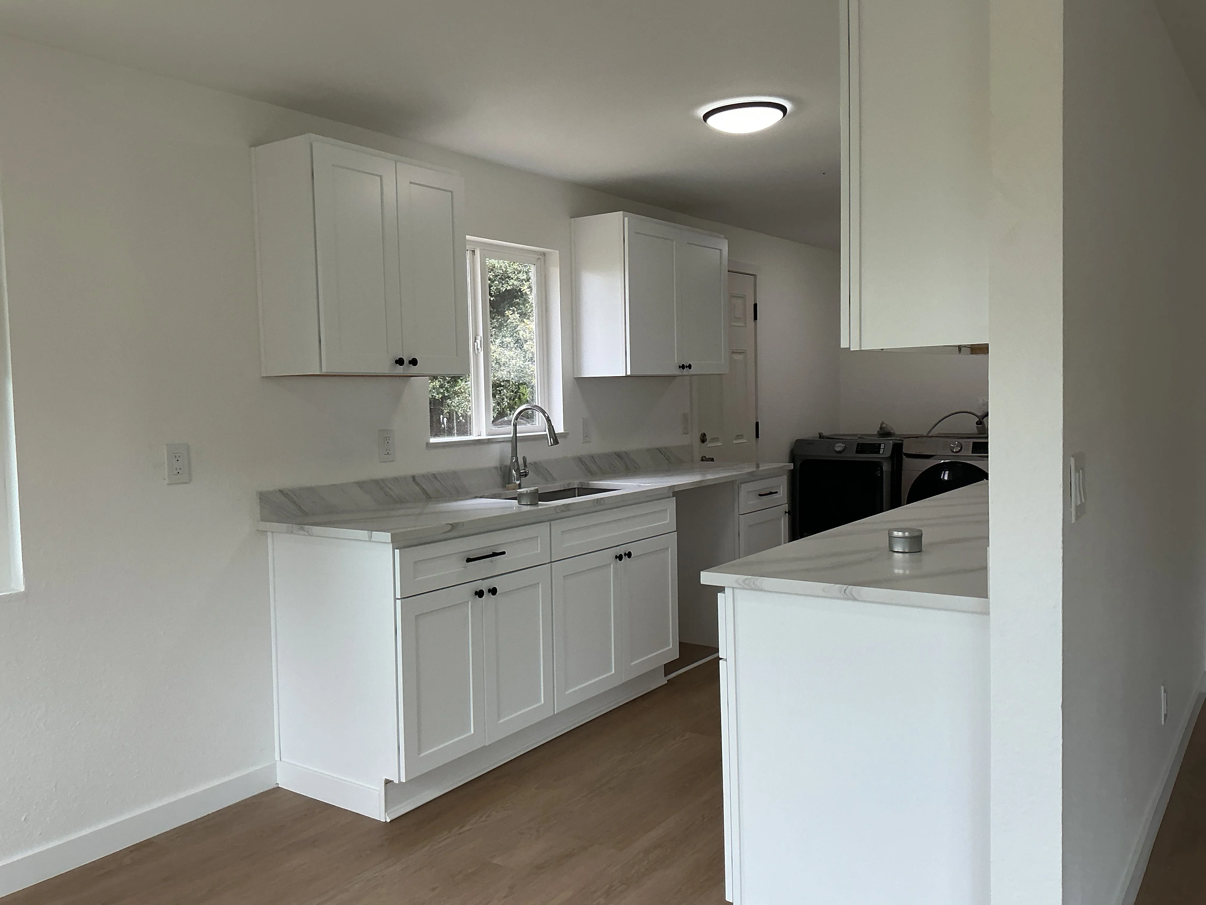White kitchen cabinets with marble countertops, island, stainless appliances, and recessed lighting