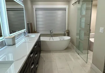 Modern bathroom with freestanding tub, dark vanity, quartz countertop, and frameless glass shower