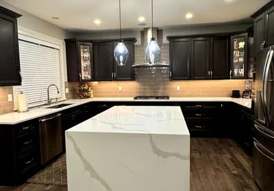 Black cabinetry kitchen with white quartz island, subway tile backsplash, and pendant lights