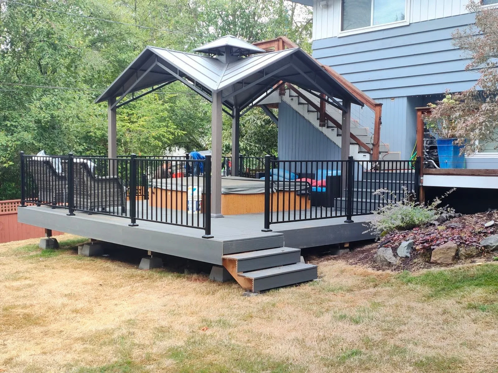 Elevated composite deck with gabled roof, black aluminum railings, and integrated stairs