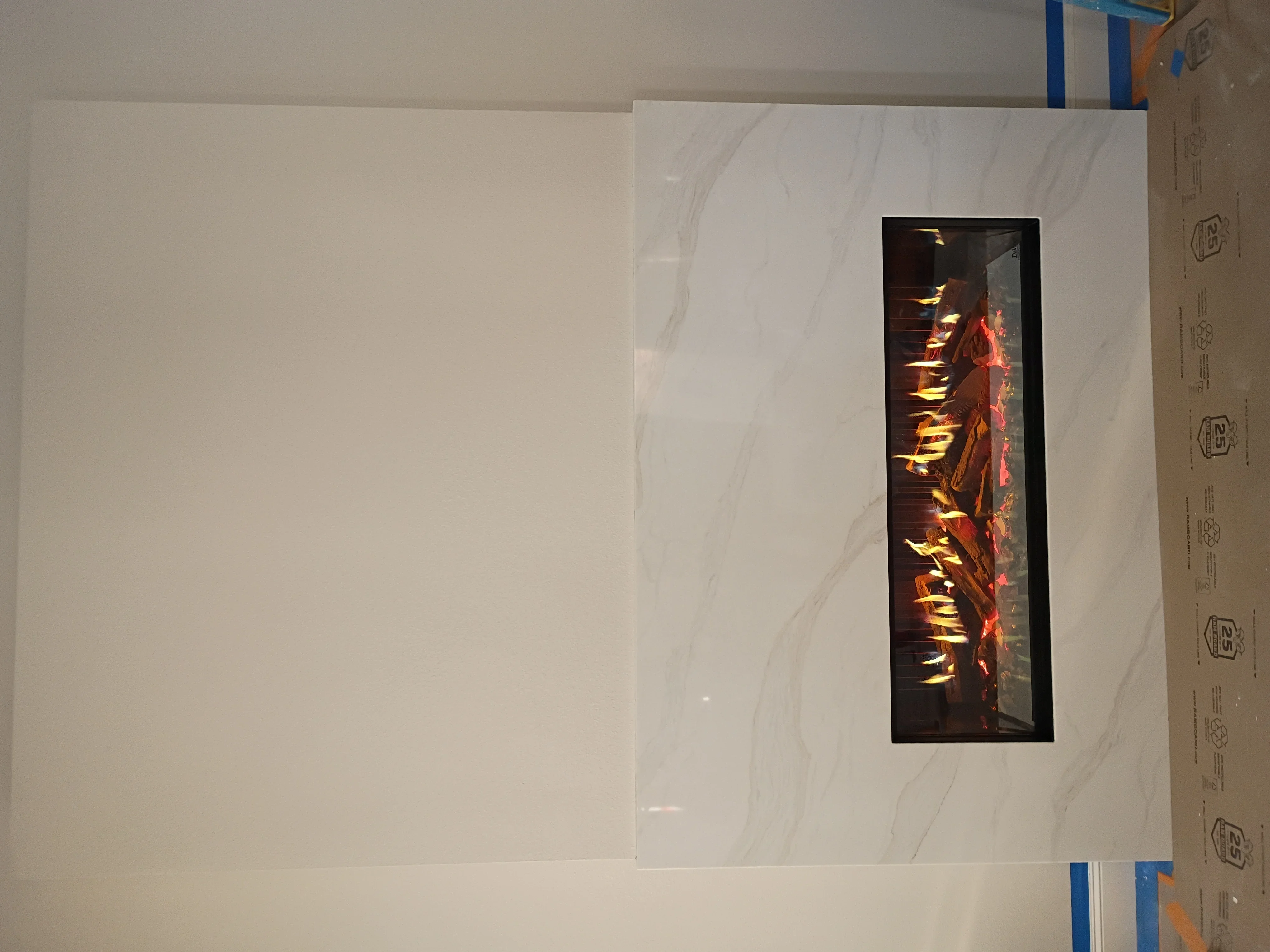 Electric fireplace with flame effect installed in marble textured wall with black frame
