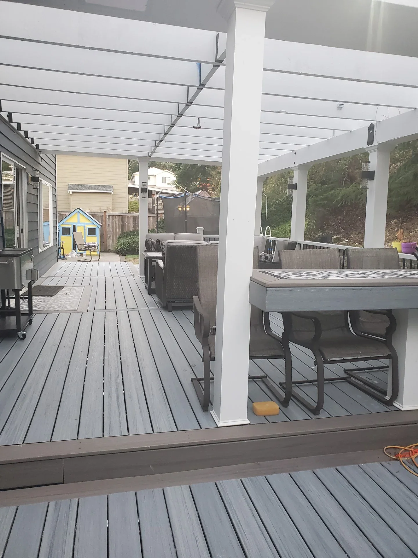 Gray composite deck with white pergola, multiple levels, and integrated outdoor furniture area