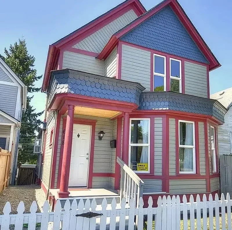 Victorian home with gray siding, burgundy trim, blue shingles, new windows, and white porch railings